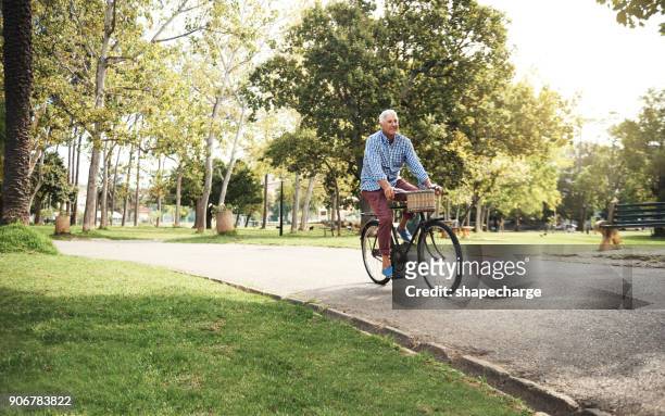 when you've got a bike, you've got everything - adult riding bike through park stock pictures, royalty-free photos & images