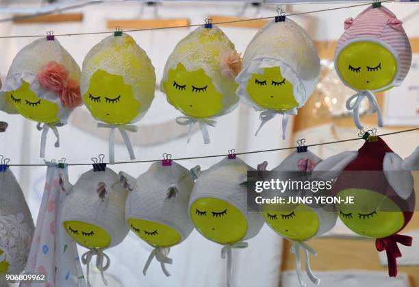 This picture taken on December 21, 2017 shows baby bonnets displayed on a booth at a baby fair in Seoul. Rapid economic growth over several decades...