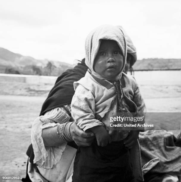 Toddler girl with his mother at the city of Otavolo, Ecuador 1960s.