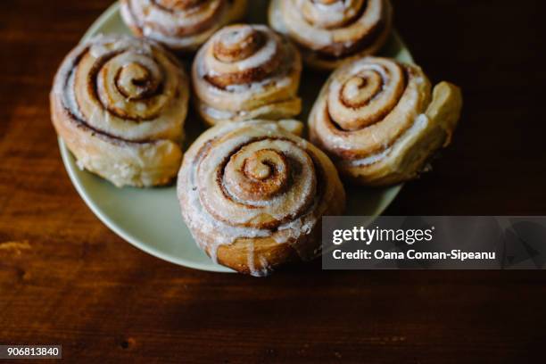 six fresh homemade cinnamon rolls with sugar glaze on a green plate - cinnamon bun stock pictures, royalty-free photos & images