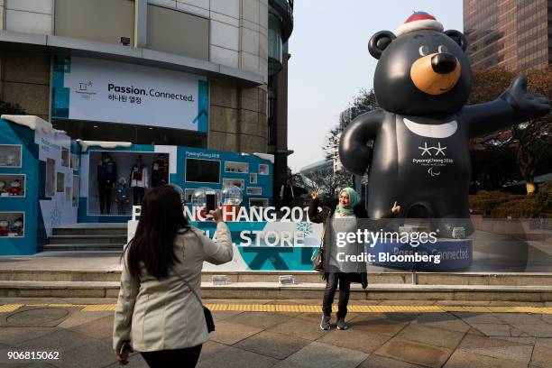 Tourists take a photograph in front of a statue of the 2018 PyeongChang Winter Paralympic Games mascot Bandabi outside an Olympic official store in...