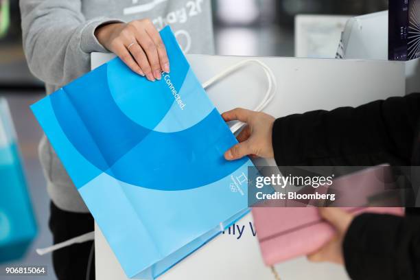 Employee, left, hands a branded shopping bag to a customer at an 2018 PyeongChang Winter Olympic Games official store inside Seoul Station in Seoul,...