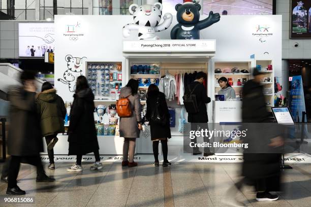 Commuters walk past customers browsing Olympic merchandise at an 2018 PyeongChang Winter Olympic Games official store inside Seoul Station in Seoul,...