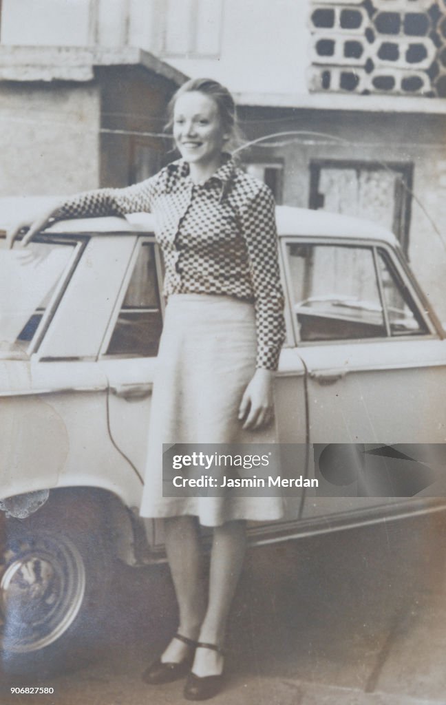 Vintage black and white photo of woman standing next to car