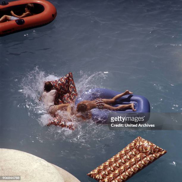 Children raving at the hotel's swimming pool with air mattresses and rubber boats, Spain early 1980s.
