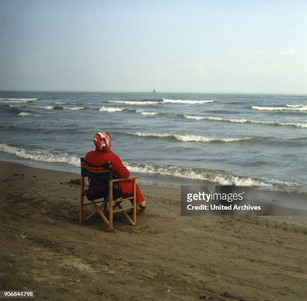 Woman sitting comfortably in a chair, facing the sea 1980s, Italy, Adria.