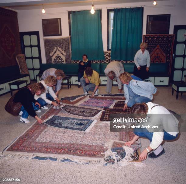 Tourists are to buy carpets as a souvenir at Kairouan, Tunisia 1980s.