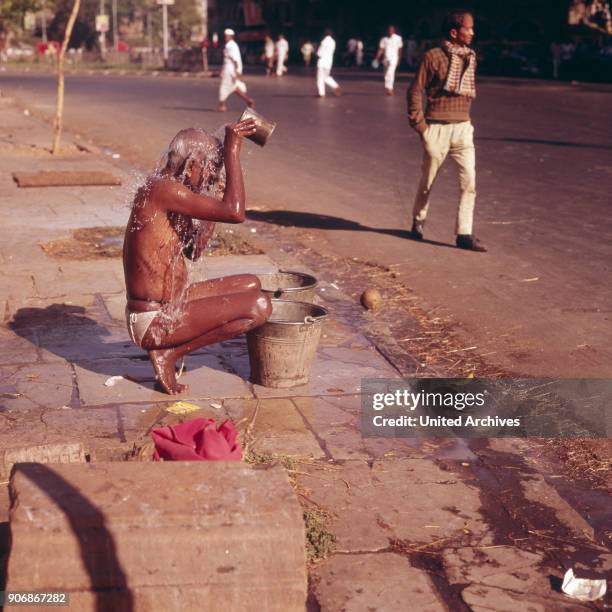 Street scene at Bombay: a man washing himself in the street, India 1970s.