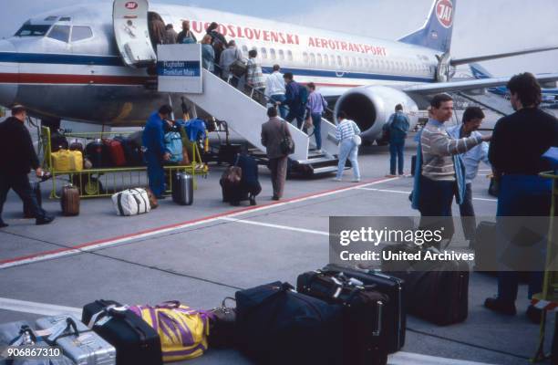 While their baggage is loaded, passengers enter their plane of the Jugoslowenski Aerotransport airline at Frankfurt airport, Germany 1980s.