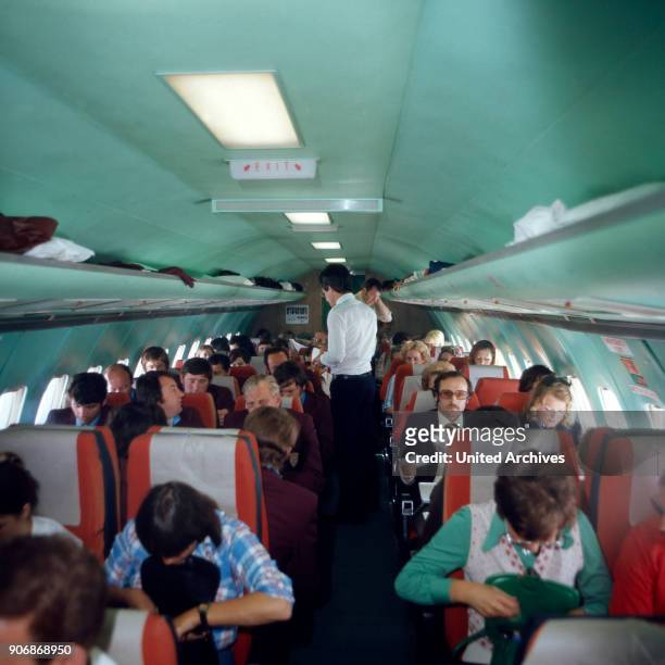 Aircraft cabin with passengers, 1980s.