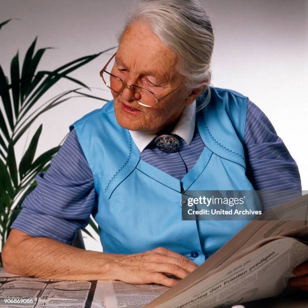 Senior woman reading a newspaper, 1980s.