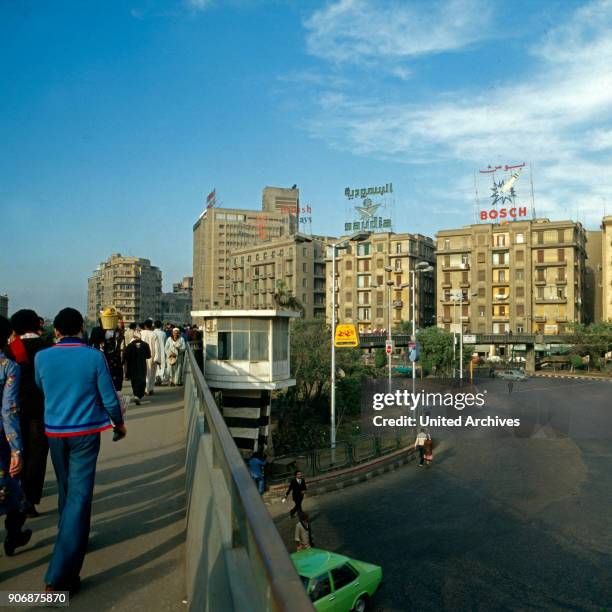 Passers by crossing a pavement bridge at Midan al Tahrir square, Cairo, Egypt, late 1970s.