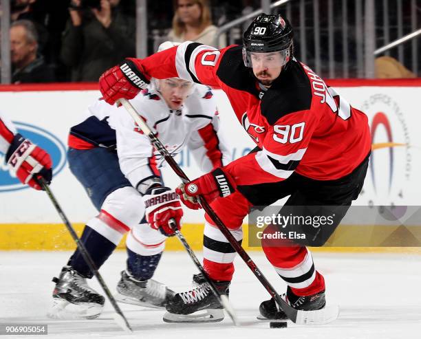 Marcus Johansson of the New Jersey Devils takes the puck as Dmitry Orlov of the Washington Capitals defends on January 18, 2018 at Prudential Center...