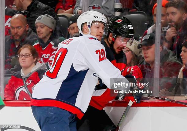 Marcus Johansson of the New Jersey Devils is checked by Lars Eller of the Washington Capitals during the game at Prudential Center on January 18,...