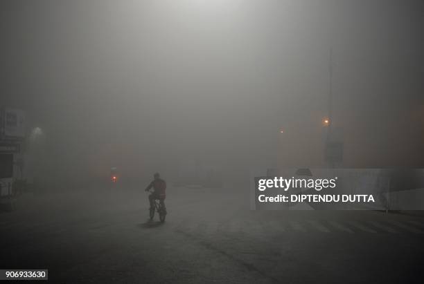 An Indian man rides a bicycle amid heavy smog in Siliguri on January 19, 2018. / AFP PHOTO / DIPTENDU DUTTA