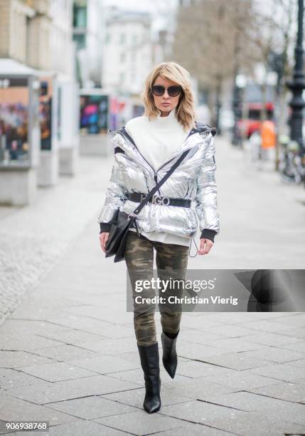 Gitta Banko wearing a silver-metallic down jacket and camouflage patterned jeans by True Religion, white cotton blouse with large, pleated sleeves...