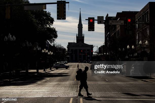 Homeless man with his pack and sleeping rolls crosses a street in Shreveport, Louisiana, United States on January 04, 2018.