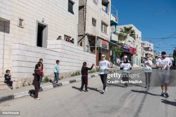 Encouraged by cheering locals, men and women run through the Al Khadr district of Bethlehem on 1st April 2016 in Bethlehem, West Bank. During the...