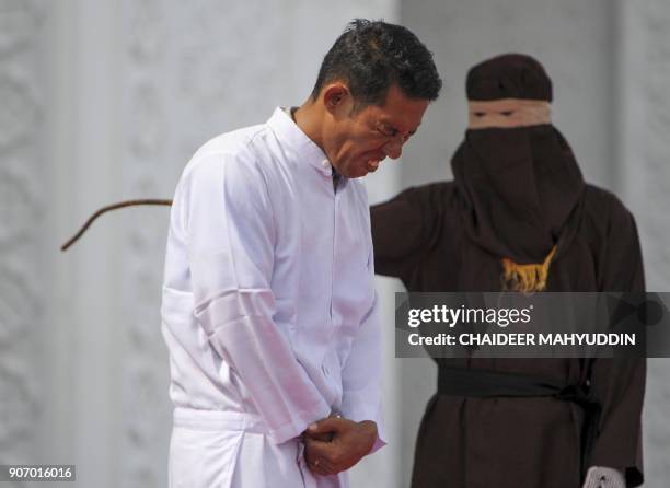 Jono Simbolon , an Indonesian Christian, grimaces in pain as he is flogged in front of a crowd outside a mosque in Banda Aceh, Aceh province, on...