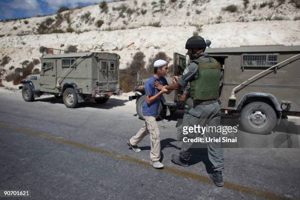 An Israeli soldier pushes away a Jewish boy after A violent clash between settlers and Israeli security forces erupted at a West Bank outpost of...