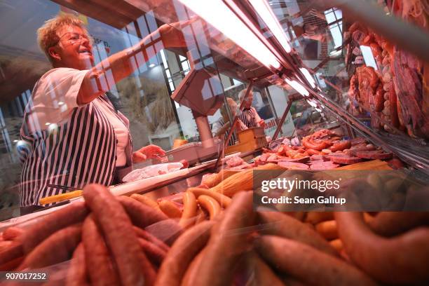 Woman at a meats and sauasges display in the Saxony hall offers a visitor a sample at the 2018 International Green Week agricultural trade fair on...