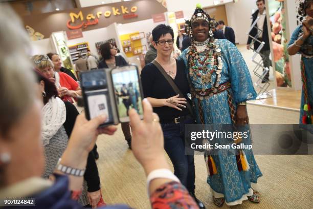 Visitor poses for a snapshot with a Moroccan musician at the 2018 International Green Week agricultural trade fair on January 19, 2018 in Berlin,...