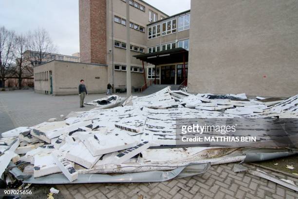 Woman looks at parts of the roof structure of a primary school lying in the schoolyard on January 19, 2018 in Halberstadt, eastern Germany, one day...