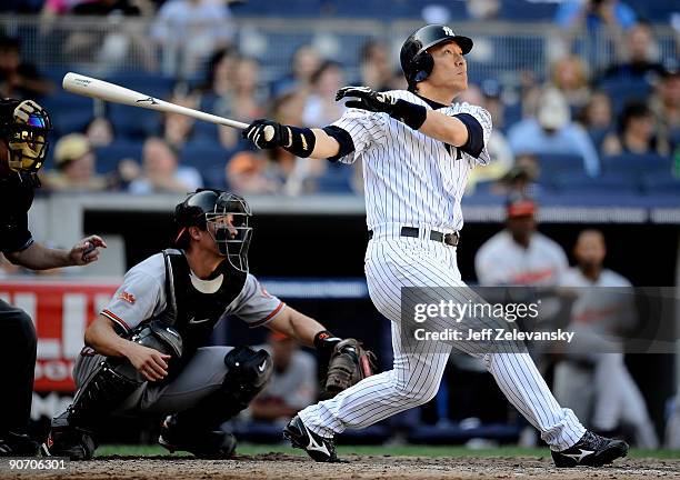 Hideki Matsui of the New York Yankees hits a three-run home run in front of Chad Moeller of the Baltimore Orioles in the eighth inning of a game at...