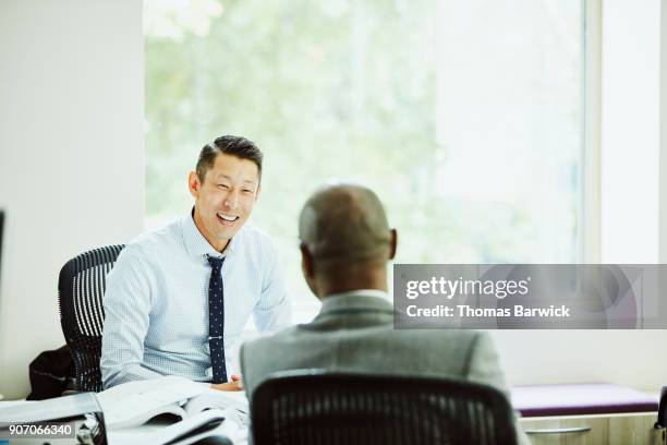 smiling businessman in discussion with client in office - financial services foto e immagini stock