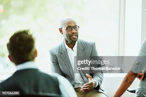 Businessman leading team during informal team meeting in office Businessman leading team during informal team meeting in office
