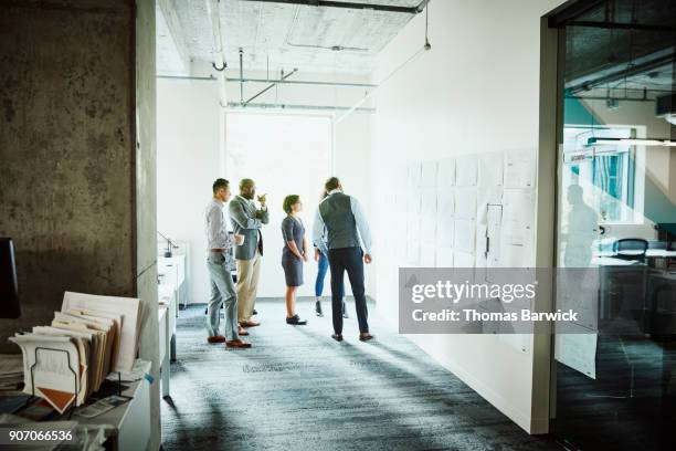 project team discussing plans posted on office wall - brainstorming wall stock pictures, royalty-free photos & images