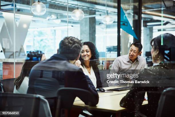 smiling businesswoman listening during client presentation in office conference room - room service stockfoto's en -beelden