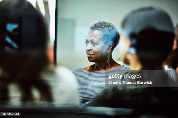 businesswoman listening to client presentation during meeting in office conference room - senior women group stock pictures, royalty-free photos & images