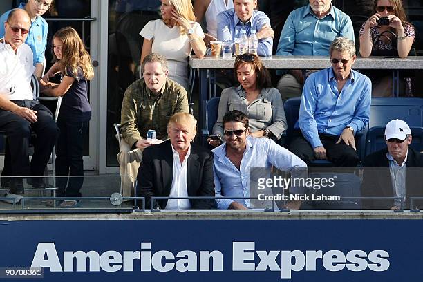 Donald Trump and actor Gerard Butler watch the match between Roger Federer of Switzerland and Novak Djokovic of Serbia during day fourteen of the...