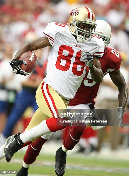 Wide receiver Isaac Bruce of the San Francisco 49ers carries the ball after a 50 yard reception past Bryant McFadden of the Arizona Cardinals during...