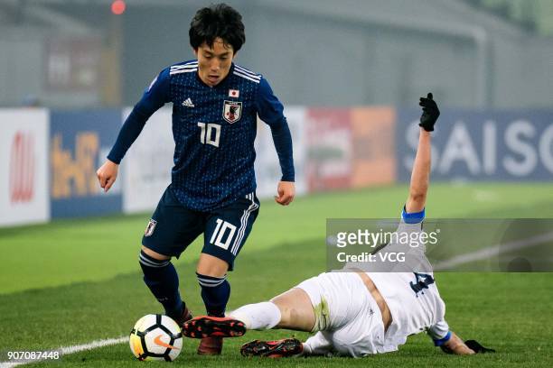 Koji Miyoshi of Japan and Akramjon Komilov of Uzbekistan compete for the ball during the AFC U-23 Championship quarter-final match between Japan and...