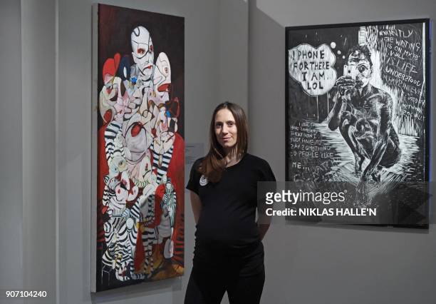 British artist Dannielle Hodson poses for a photograph flanked by her paintings, The Flasher , and & 'like' me at Sotheby's auction house in central...