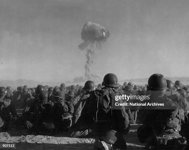 Troops of the U.S. Army 11th Airborne Division watch a plume of radioactive smoke rise November 1, 1951 after a blast at Yucca Flats, Nevada .