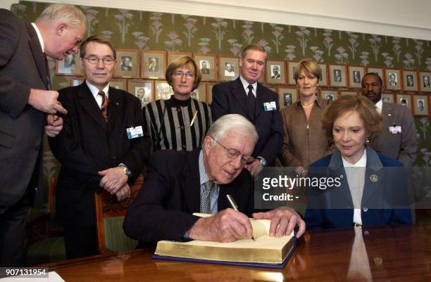 Nobel Peace Prize winner and former US president Jimmy Carter signs the guestbook in the Nobel Institute in Oslo, 09 December 2002, next to his wife...
