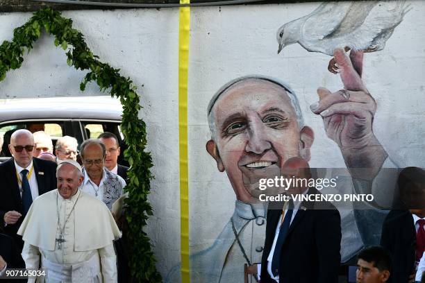 Pope Francis walks near a graffiti depicting his portrait as he arrives to meet with children at "Hogar Principito" Children's home, in the Peruvian...