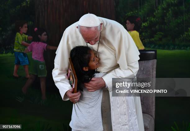 Pope Francis is hugged by a girl during his visit to the children's home "Hogar Principito", in the Peruvian city of Puerto Maldonado, on January 19,...