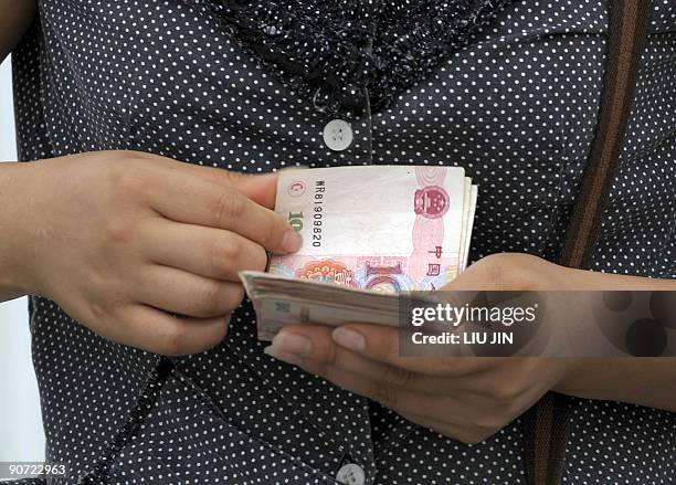 China-economy-finance-IPO-company,ANALYSIS by Allison Jackson This photo taken on September 11, 2009 shows a woman counting Chinese banknotes along a...