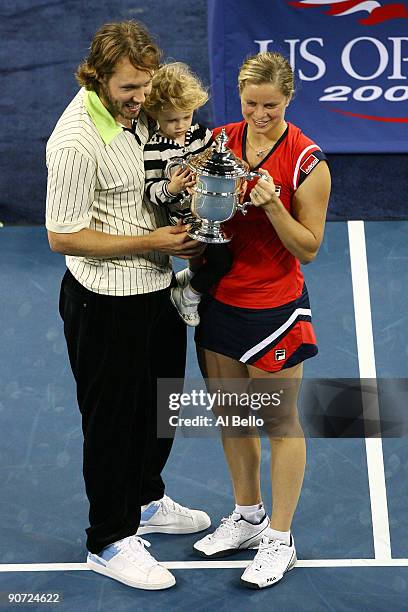 Kim Clijsters of Belgium poses with the championship trophy alongside husband Brian Lynch and daughter Jada after defeating Caroline Wozniacki of...