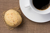 Pao de Queijo is a cheese bread ball from Brazil. Also known as Chipa, Pandebono and Pan de Yuca. Snack and cup of coffee on wood, overhead.