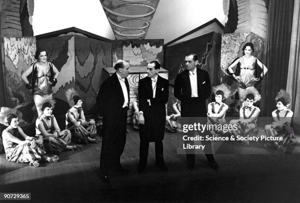 Three Music Hall performers flanked by chorus girls on stage, c 1920s.