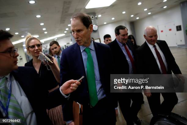 Sen. Ron Wyden speaks with reporters as he and Sen. Ben Cardin , at right, and Sen. Joe Donnelly , center, walk to a Democratic Caucus meeting at the...