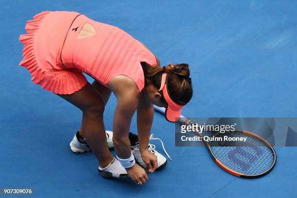 Lauren Davis of the United States removes her shoe after injuring her foot in her third round match against Simona Halep of Romania on day six of the...