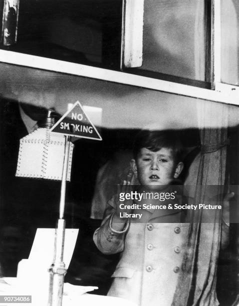 Prince Charles stands at the window of the royal saloon and waves to onlookers before the train departs Aberdeen for London.