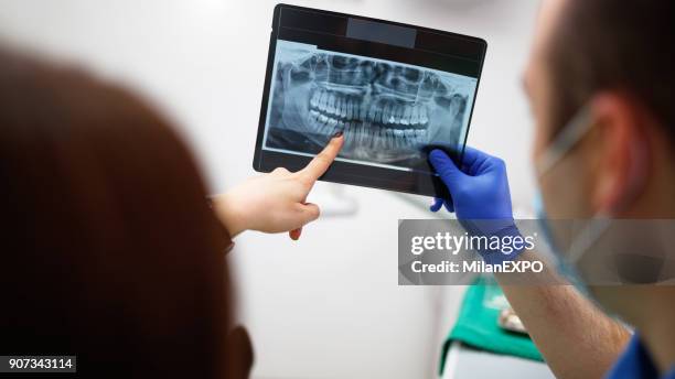 dentist showing a patient her x-ray - dental imaging stock pictures, royalty-free photos & images