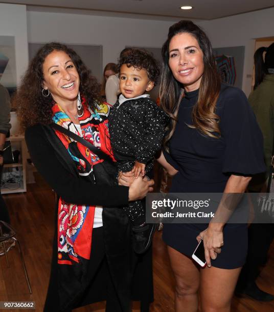 Nicole Tuck, holding son Asahd Khaled poses with FYI Brand Group Founder Tammy Brook at the "For Your Information" Pop-Up Art Show hosted by FYI...